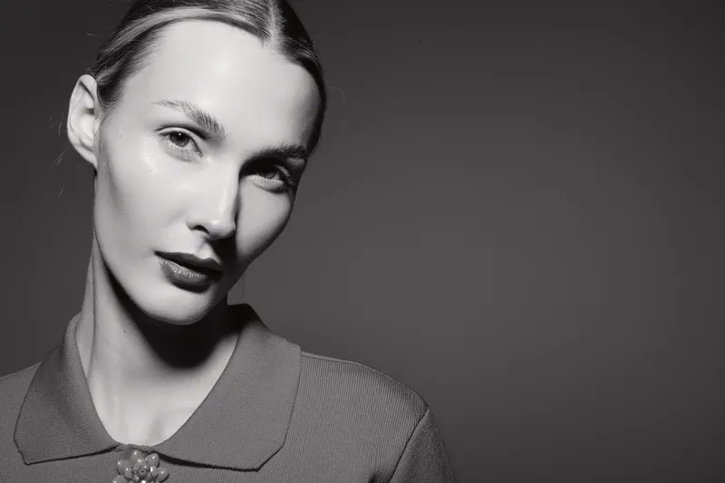 Portrait of a young white woman with pale skin and slicked-back hair wearing a textured top in a monochrome studio. Concept for beauty, fashion, and elegance.