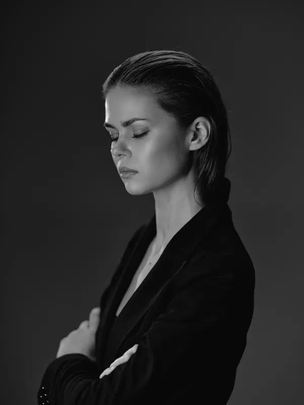 Black and white portrait of a thoughtful woman with crossed arms, expressing calmness and introspection.
