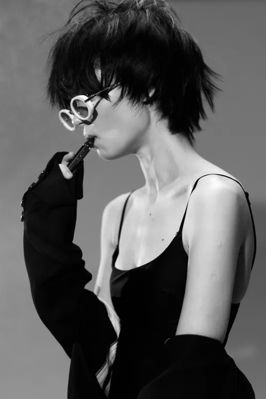 Black and white portrait of a young woman with short hair wearing glasses and a sleeveless top