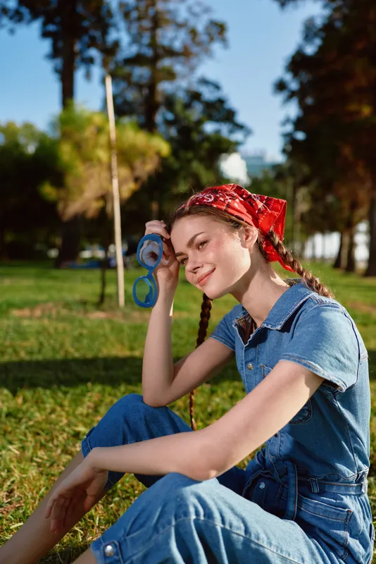 Lifestyle woman with modern boho-western denim street style sitting outdoors in natural daylight, film color tones enhancing casual and relaxed mood.
