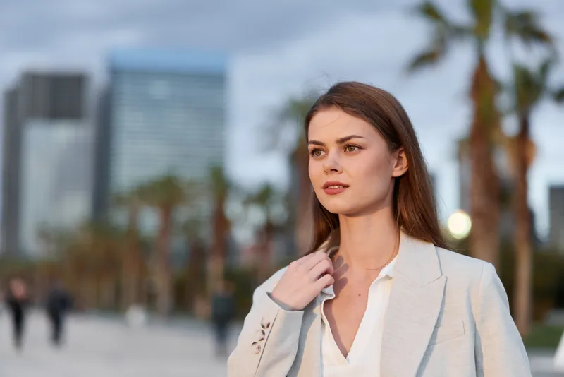Confident businesswoman outdoors in a professional setting, dressed in a stylish suit, radiating poise and elegance amidst an urban backdrop.