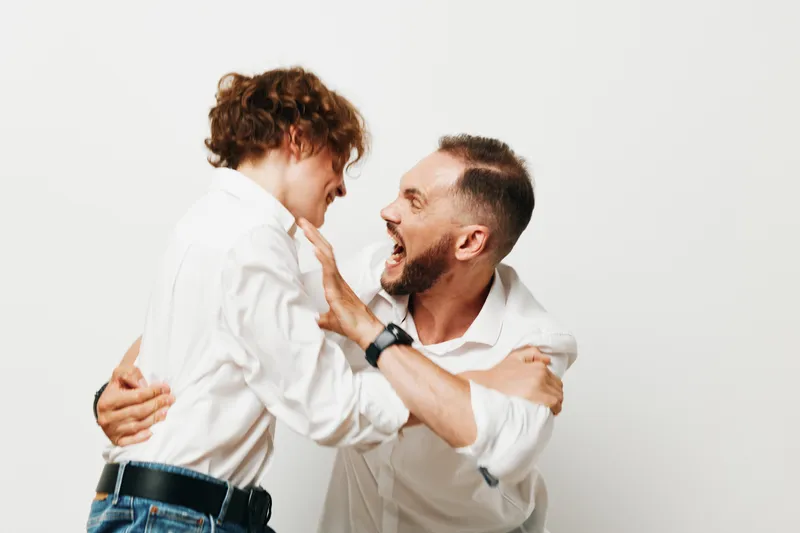 A businessman and professional man share an energetic moment against an isolated colored background, signaling confidence and enthusiasm. The scene highlights strong interaction and positive