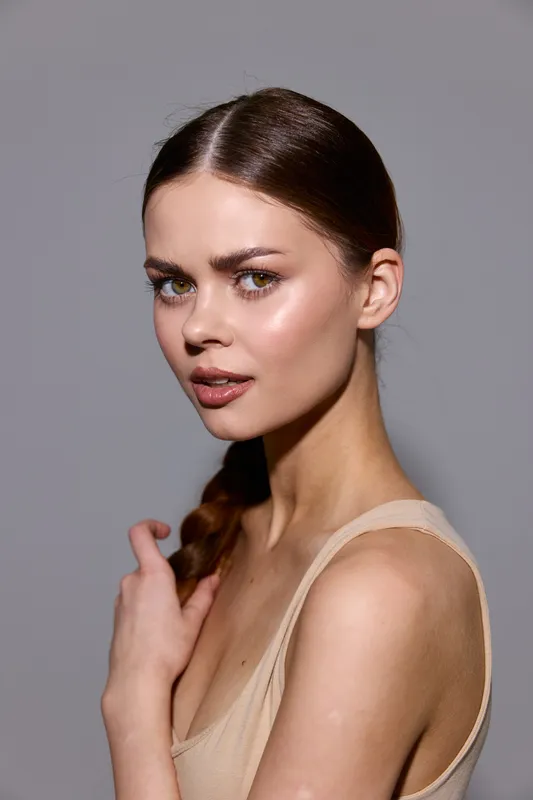 Beauty woman with clean skin and natural makeup posing with soft lighting and neutral background, highlighting fashion and elegance in a minimalist style.