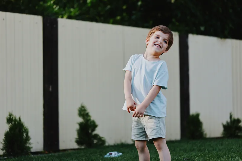 Joyful young boy playing outdoors in a sunny garden, showcasing happiness and carefree childhood spirit, capturing the essence of playful moments.