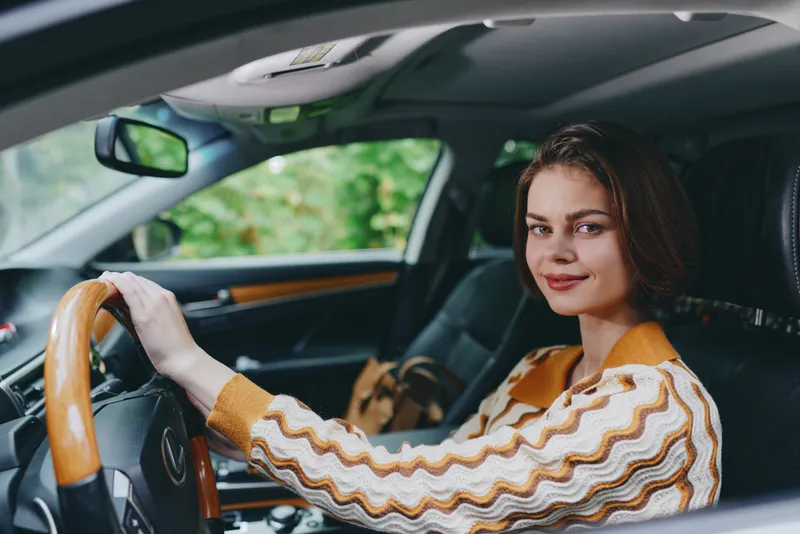 Car, driver, woman, smile a cheerful woman sits in the driver's seat with her hand confidently on the steering wheel, radiating joy and readiness for a journey