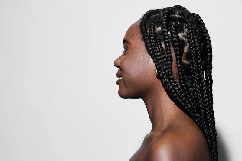 Profile portrait of a young woman with braided hair against a minimalist background, showcasing beauty and self confidence in a modern aesthetic