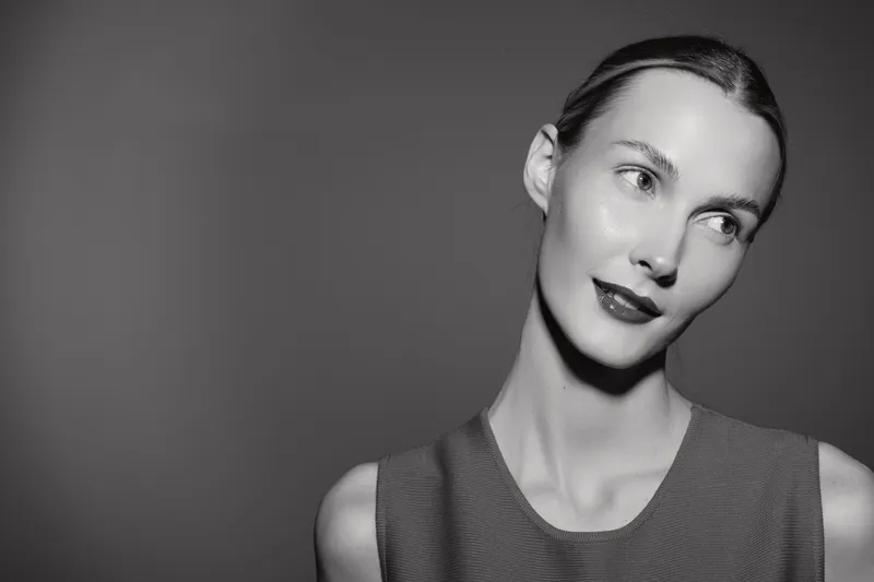 Portrait of a fair skinned Caucasian woman with slicked back hair wearing sleeveless top looking aside in monochrome studio. Concept of beauty, elegance, and fashion.
