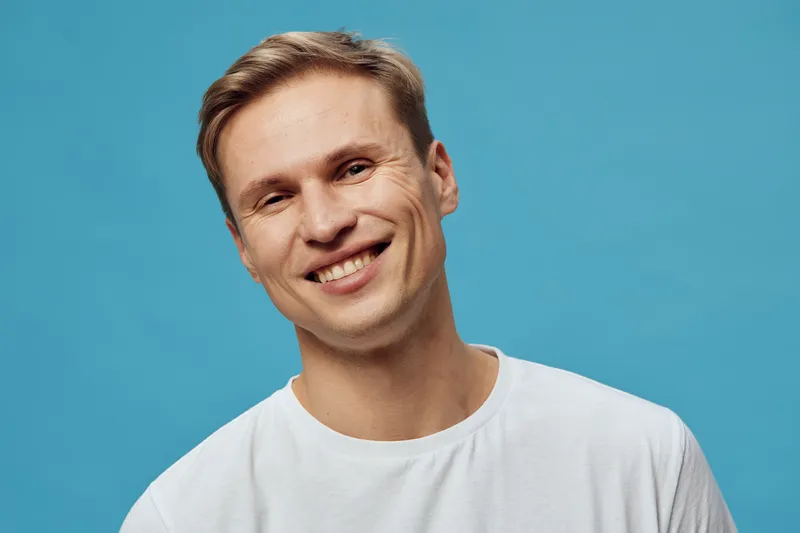 Smiling man digital detox wearing white t-shirt isolated blue background happy portrait mental health concept