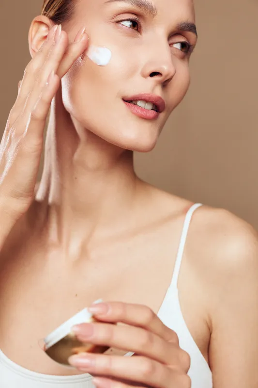 Young woman applying face cream on clean skin, skincare routine, natural beauty, soft lighting, close up, healthy complexion, gentle touch, minimal makeup, wellness concept