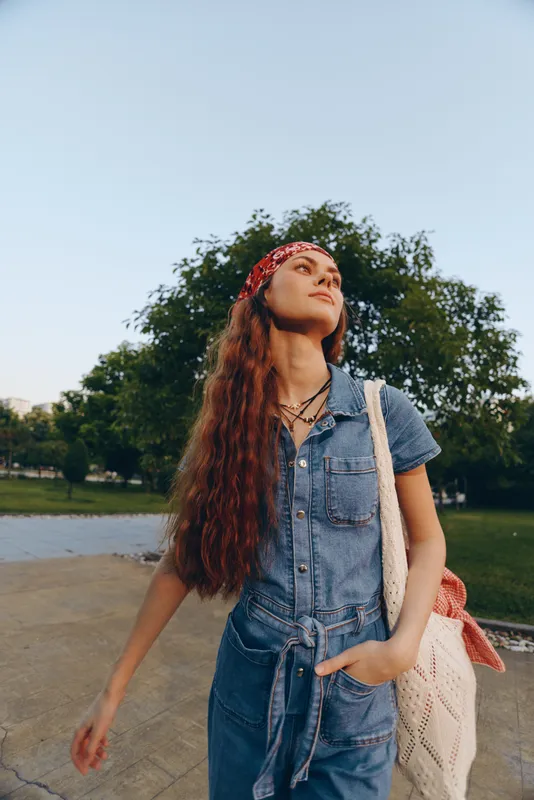 Modern boho-western denim street style woman with long hair, red bandana, and natural outdoor background, styled with film color tones for a trendy lifestyle look.
