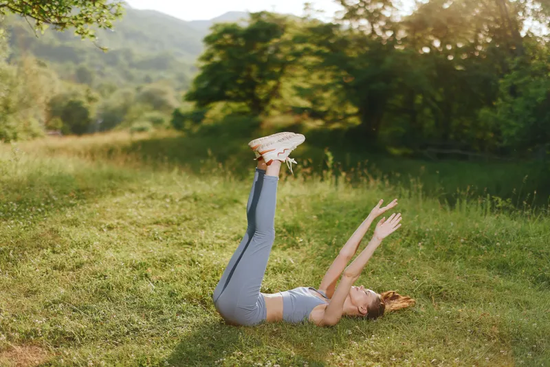 Young woman practicing yoga poses outdoors in a green field, showcasing a healthy lifestyle and fitness concepts in natural light
