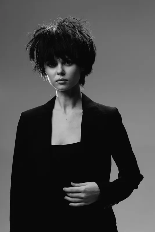 Black and white portrait of a young woman with short hair wearing a dark blazer, expressing calm and serious mood.