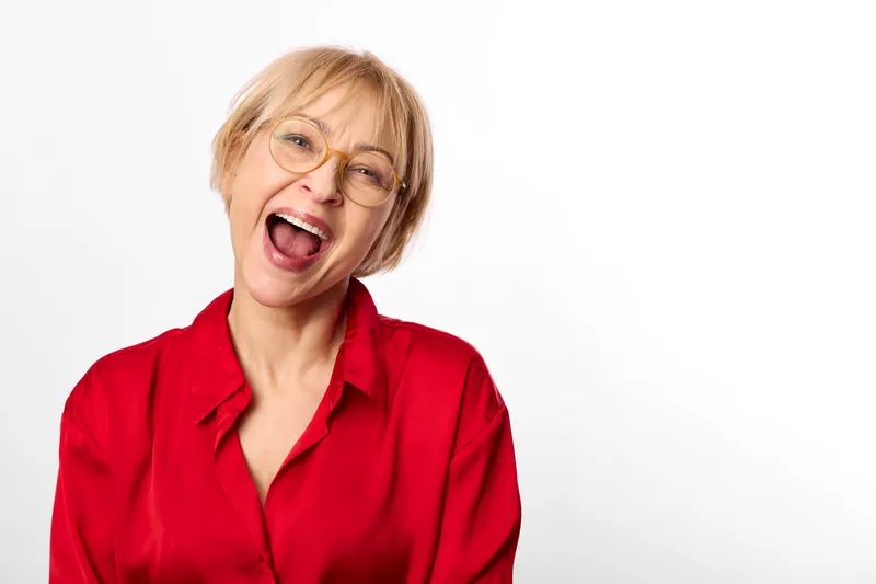 Elderly woman in red portrait shouting shows emotion with stress and anger in a studio headshot on clean white background