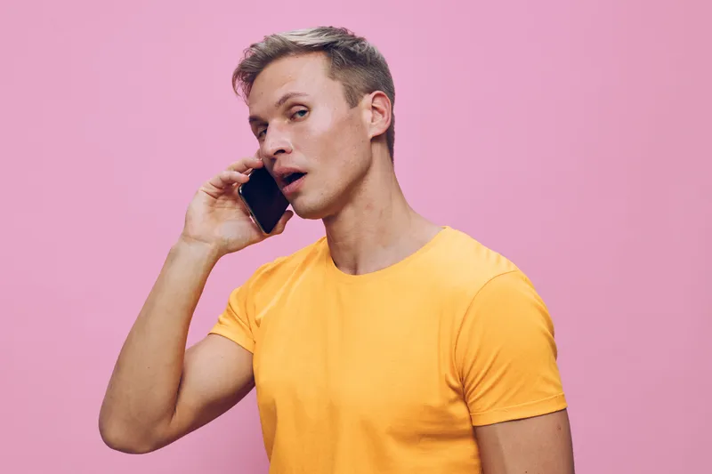 young man talking phone casual orange t-shirt communicate talking smartphone pink background digital nomad concept