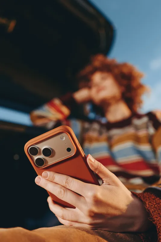 Woman lifestyle smartphone hand portrait casual travel technology communication phone, relaxed car interior with window light, blurred background, selective focus on screen, sunlit