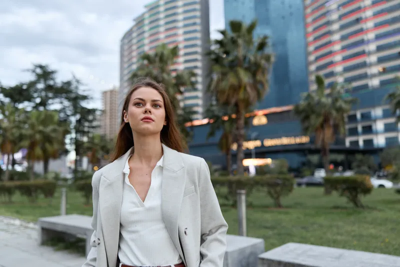 Confident businesswoman walking in a modern urban environment, showcasing professionalism and ambition with sleek attire and a determined expression.