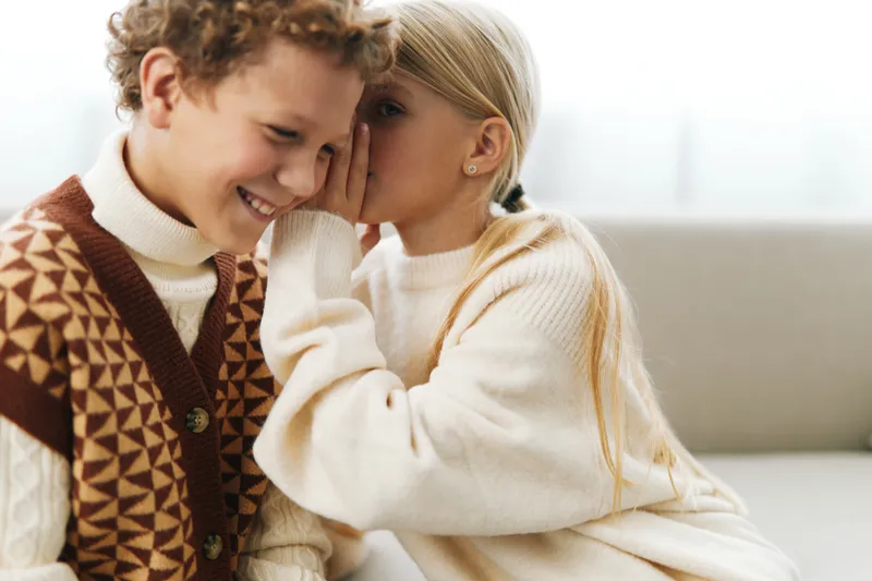 Authentic scene of children at school sharing a secret laugh, capturing a genuine lifestyle moment and a playful game spirit in everyday life.