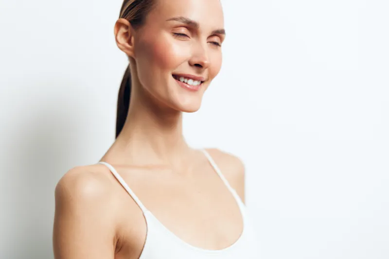 Woman portrait, smiling beauty closeup skincare of young woman in white tank top, clean skin, relaxed spa mood, soft light, isolated on white background, copyspace wellness