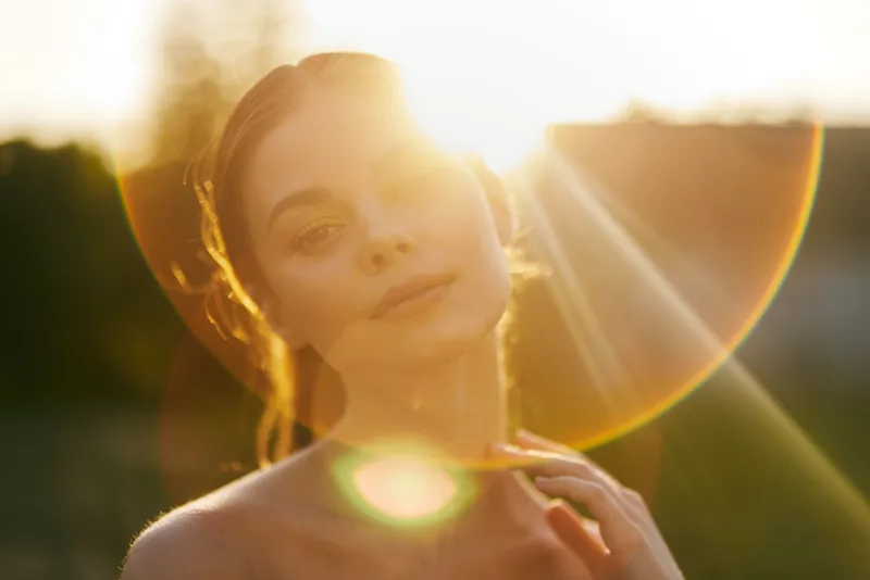 Young woman enjoying a sunset, with soft light illuminating her face and a dreamy expression, ideal for serene lifestyle concepts and summer themes
