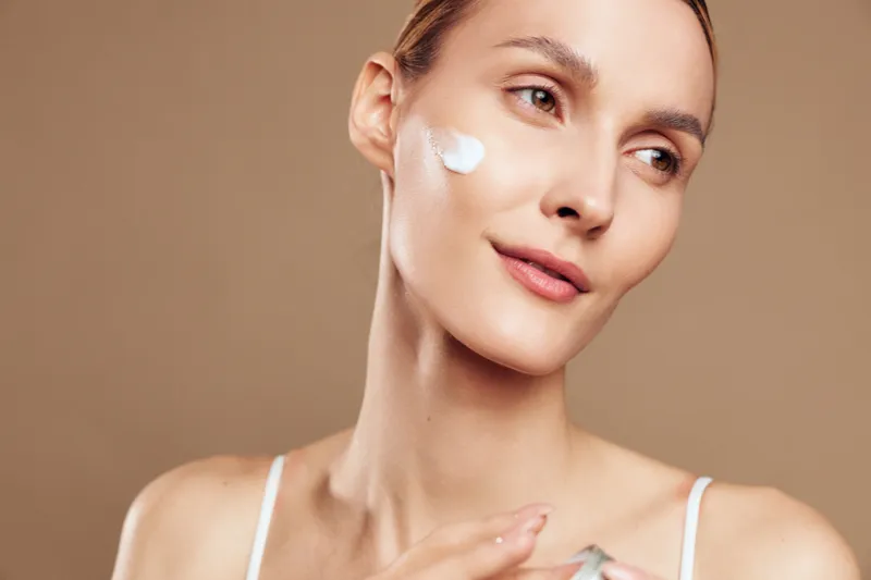 Woman skincare beauty face cream treatment cosmetics spa routine hygiene, close up portrait with moisturizer on cheek, calm expression showing personal care and wellness