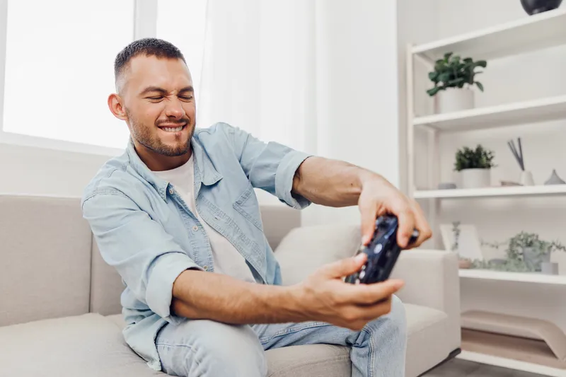 Frustrated man enjoying gaming at home, reflecting on digital detox, mental health, and the blurred line between work and personal life in today’s tech-driven world.