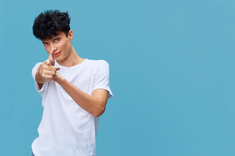 young man pointing with fingers smiling confidently wearing casual white t-shirt isolated on blue background