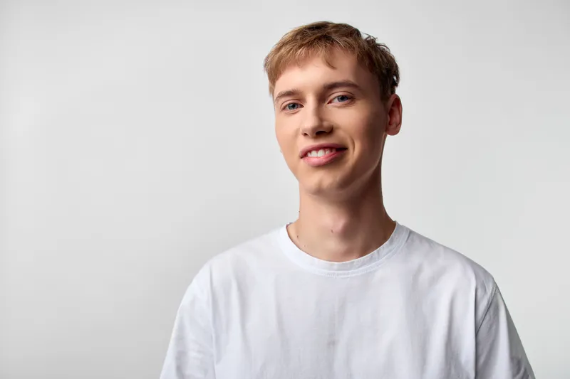 Smiling man wearing a white t shirt in a bright studio exudes friendly confidence, ideal for lifestyle, marketing, or casual branding photography in clean settings