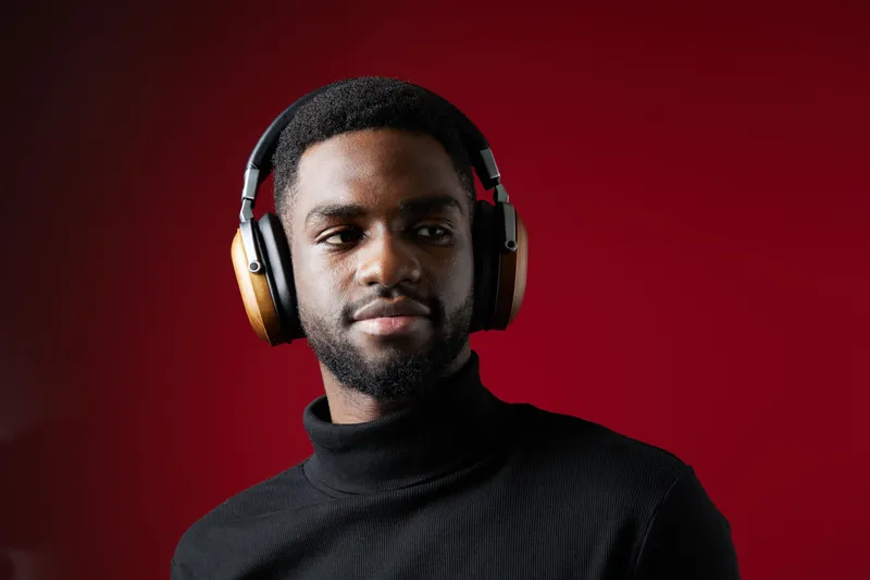 A young Black man wearing stylish headphones, exuding confidence against a bold red background, perfect for music or lifestyle projects