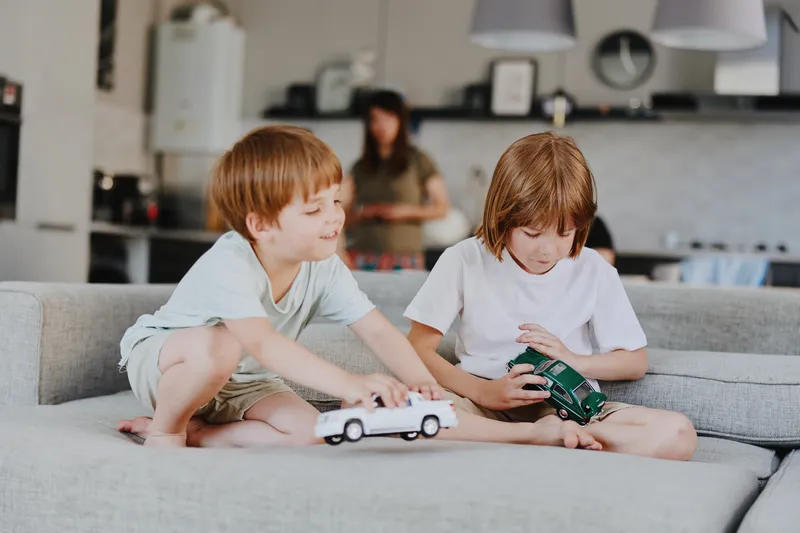 Two playful boys enjoying their toy cars in a cozy living room, surrounded by a warm atmosphere and minimalist decor, perfect for family moments.