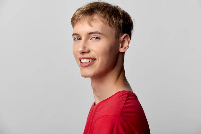 Young man with a friendly smile wearing a red shirt in a clean studio, casual pose, bright lighting and a simple background, ideal for lifestyle or fashion projects