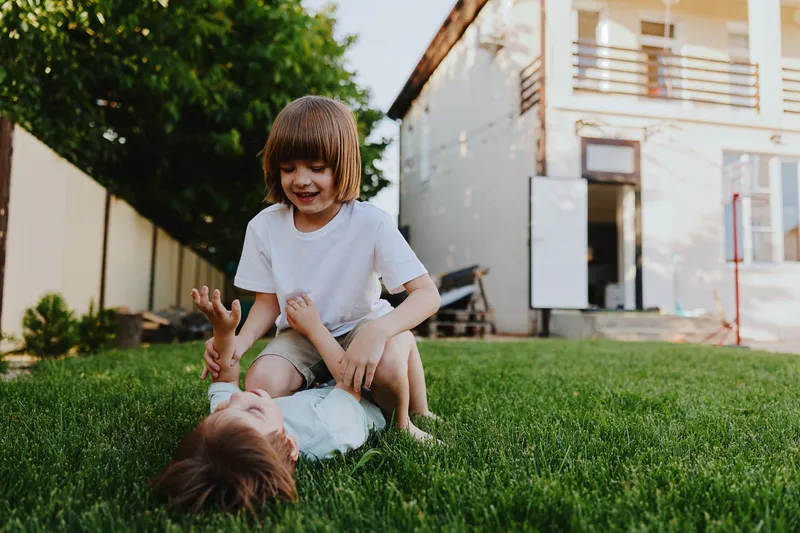 Playful children enjoying a sunny day outdoors in the garden, laughing and having fun while playing together on the grass.