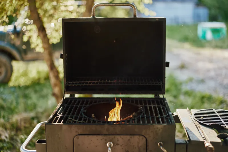 Outdoor barbecue grill with flames, showcasing summer cooking and vibrant nature background, perfect for celebrating gatherings and outdoor events
