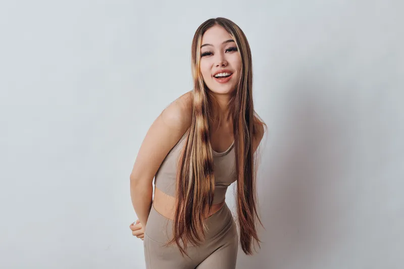 Young woman with long braids smiling and posing in casual outfit against plain background. Beauty, hairstyle, fashion and happiness in studio for portrait photography and lifestyle.