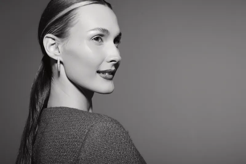 Portrait of a young white woman with fair skin smiling and looking sideways in studio. Concept of beauty, fashion, and confident female model with natural makeup.