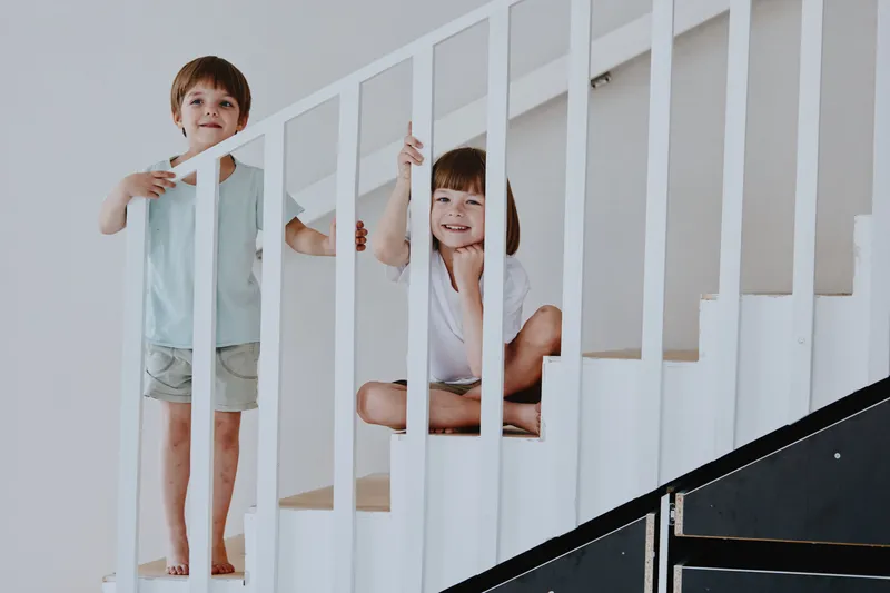 Playful children enjoying time on a staircase, smiling happily as they explore their surroundings with carefree joy and excitement.
