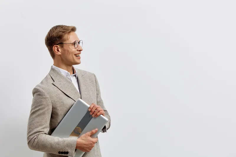 smiling caucasian man holding laptop in beige jacket wear glasses look side isolated on white background digital nomad work concept