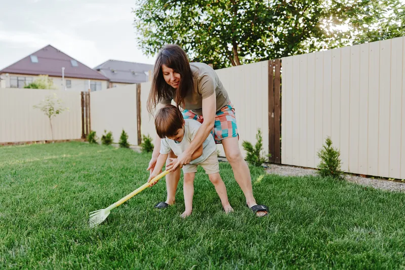 Caring woman playing with her son in the backyard, enjoying outdoor activities, surrounded by greenery and warm sunlight, creating joyful memories together.