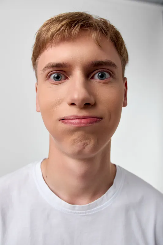 Funny expression, surprised face, young man in a white shirt, closeup shot showing playful mood and curious vibe, suitable for humor, social media, and creative stock use