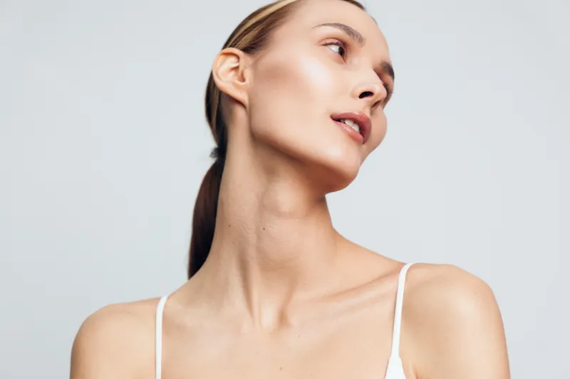 Young woman with clear skin looking sideways, natural makeup, soft lighting, smooth complexion, minimalistic background, elegant pose, beauty portrait, health care concept