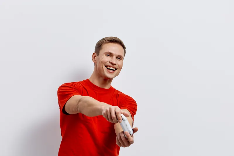 Smiling man wearing red t-shirt holding game controller playing video game digital detox happy expression isolated on white background technology concept
