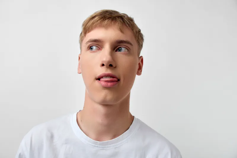 Youth, male in a white tee looks to the side, showing curiosity and casual confidence for lifestyle, fashion and everyday moments, relaxed expression and modern vibe.
