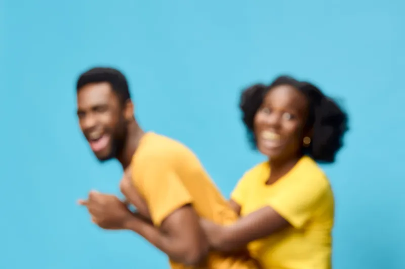 Happy couple in matching yellow outfits against a bright blue background, celebrating joy and connection with playful expressions, perfect for love and happiness themes