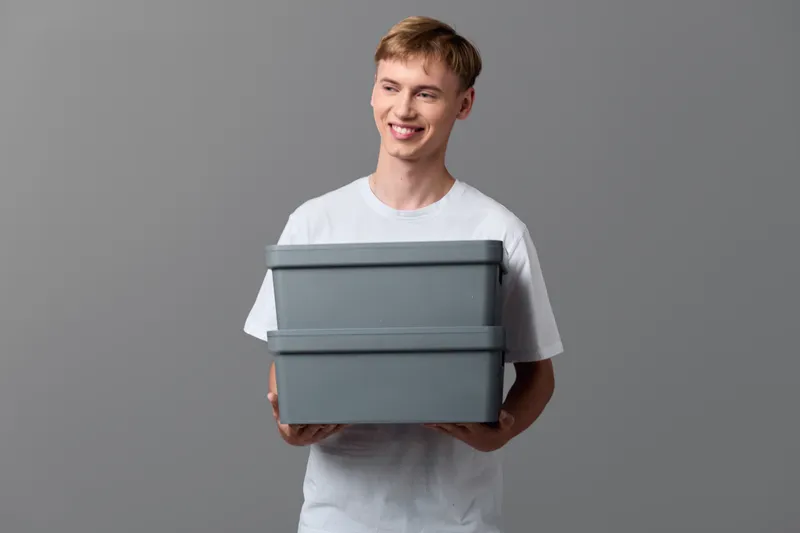 Boxes, storage, containers, organization, packaging, home, tidy, indoor, stacking, moving, casual, adult, smiling with two gray storage boxes illustrating home organization and light moving tasks in
