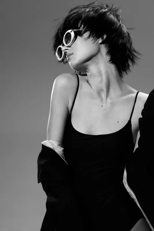 Black and white portrait of stylish woman wearing sunglasses and elegant dress