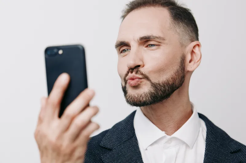 A professional man in a suit holds a smartphone on a bright colored background, exuding confidence and focus as he engages in a moment of decision, creating a strong business portrait on an isolated