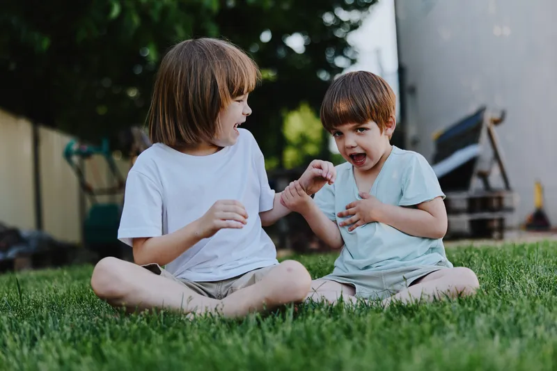Happy children playing together outdoors, enjoying a sunny day with laughter and joy. The vibrant green grass adds to the cheerful atmosphere of the scene.