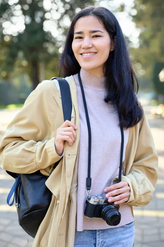 Camera, photography, woman with backpack walking outdoors, casual fashion and daylight, campus stroll, smile, hobbyist photographer, travel vibe, everyday style, lifestyle moments