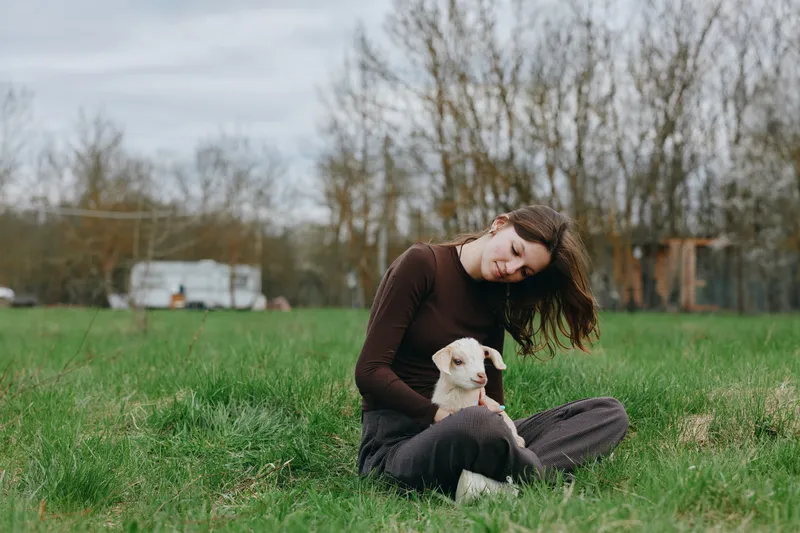 Caring woman sits on grass outdoors with a gentle dog beside her in a sunlit park, capturing a calm lifestyle moment focused on companionship, nature, and relaxation