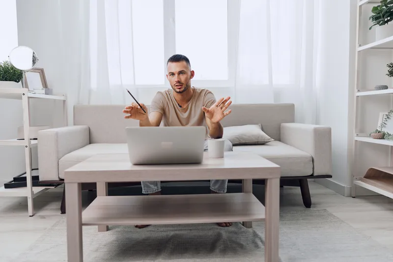 Engaging man working remotely at home, showcasing modern lifestyle, productivity, and comfort in a minimalistic environment filled with natural light.