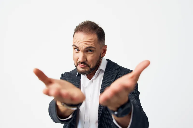 A professional man in business attire extends a welcoming gesture against an isolated white backdrop, conveying confidence, focus, and approachable leadership suitable for corporate communications.